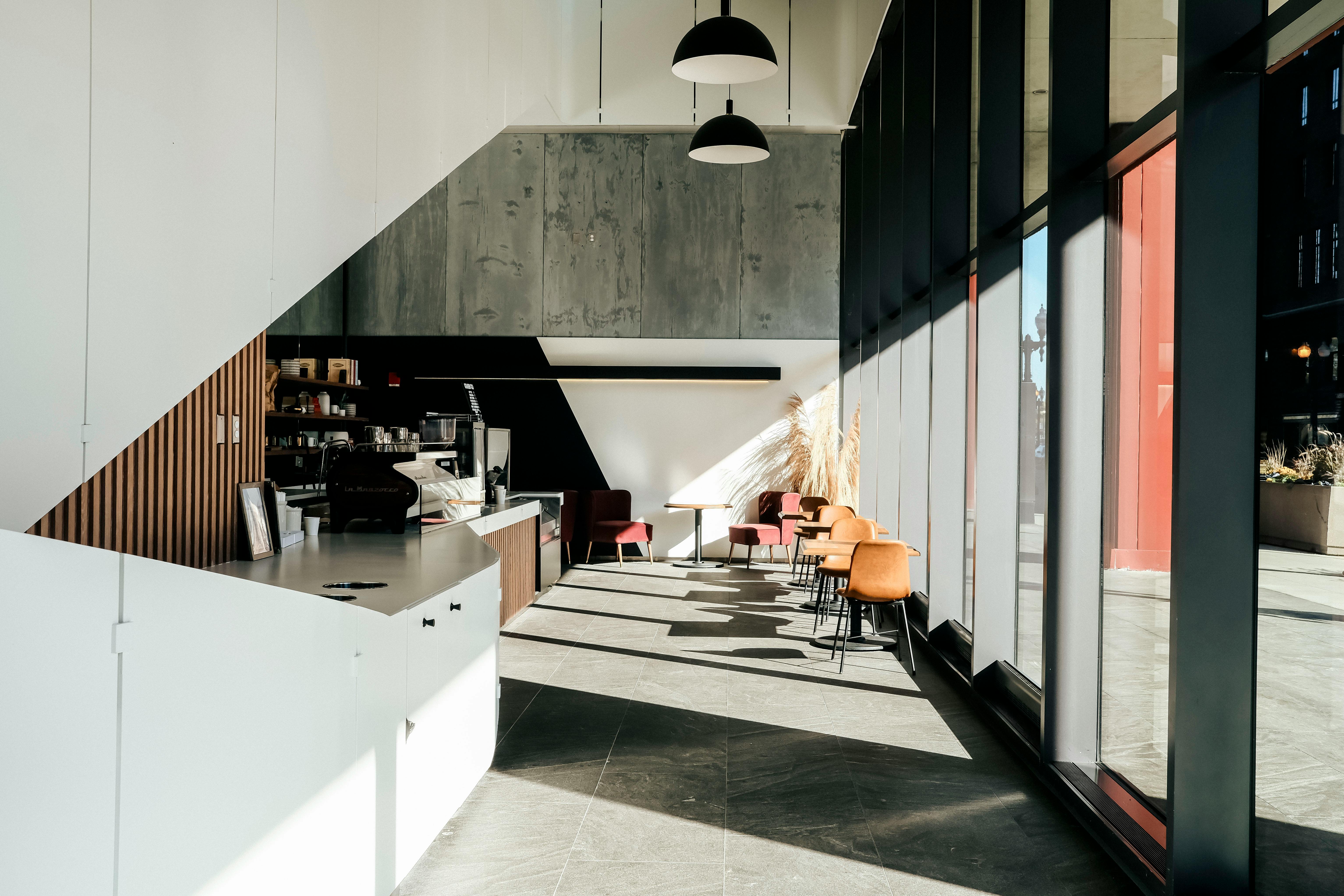 Sunlit modern cafe interior with minimalist decor and large windows, illustrating cafe website design examples that win walk-ins and pickup orders.