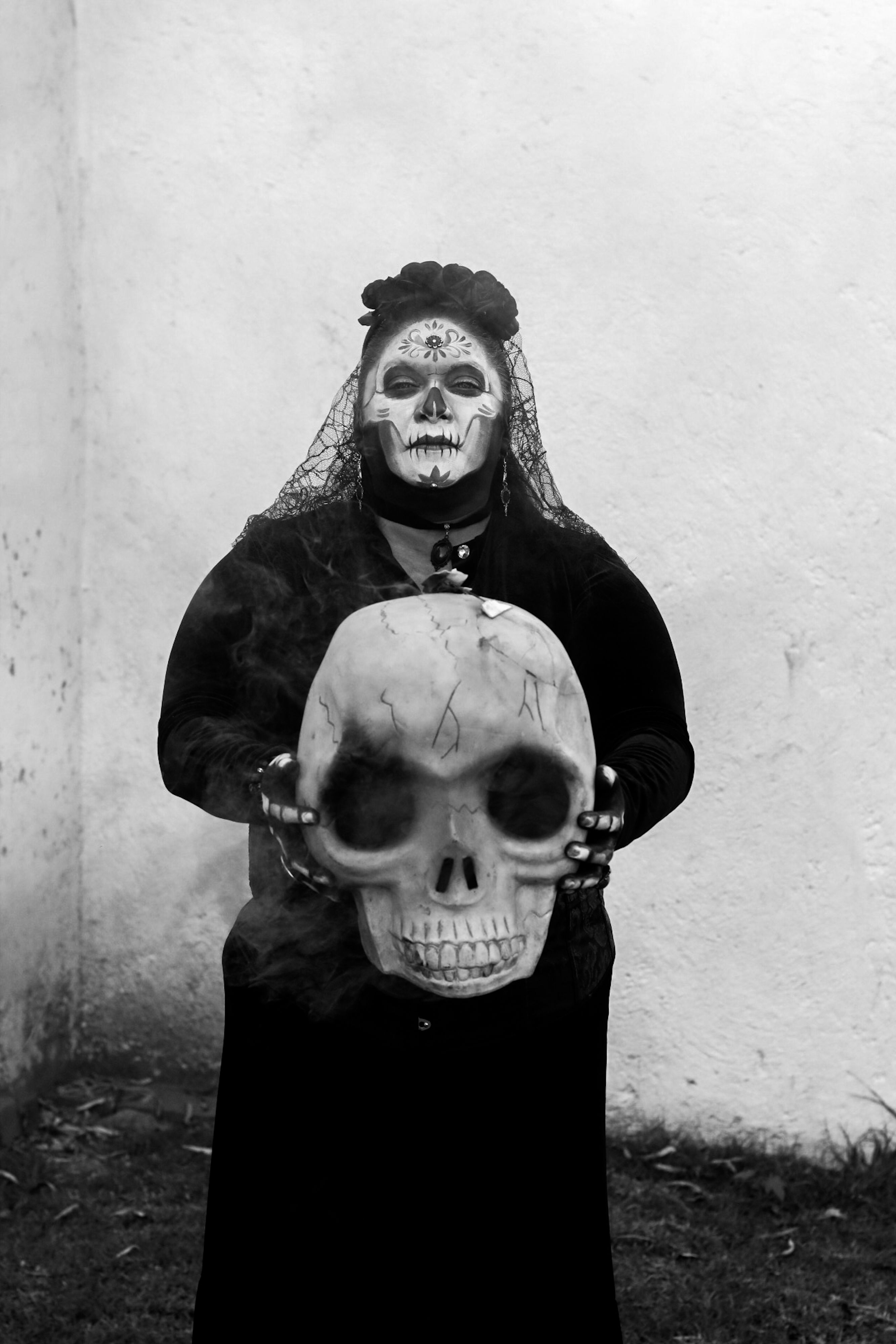Black and white photo of a person in ceremonial attire holding a skull.