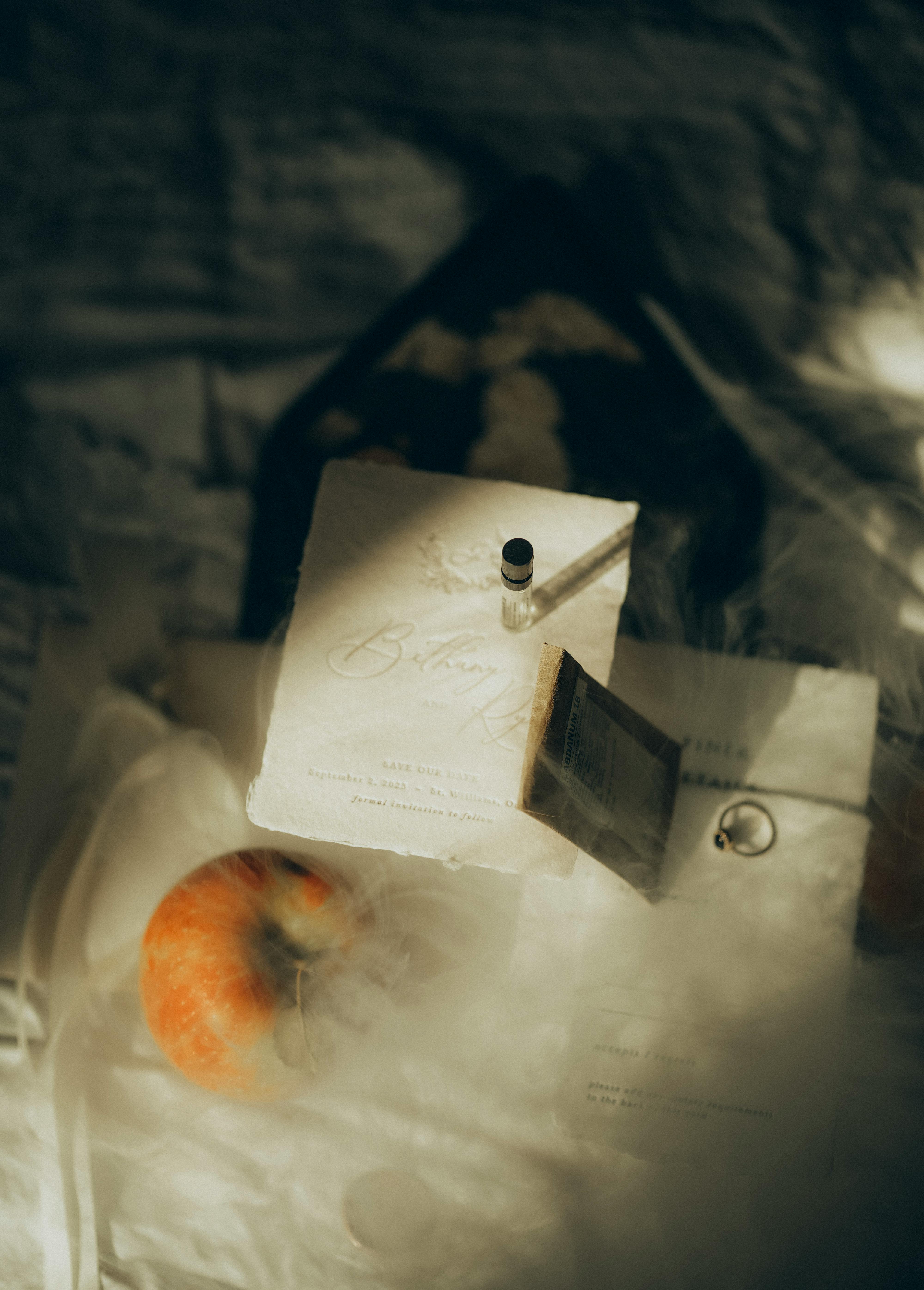 Kostenlos Künstlerisches Flatlay mit einem Apfel, Einladungen und einem Ring in sanfter, warmer Beleuchtung. Stock-Foto