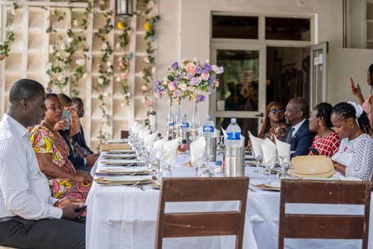 A diverse group of adults enjoying an elegant outdoor dining setup with floral decorations.