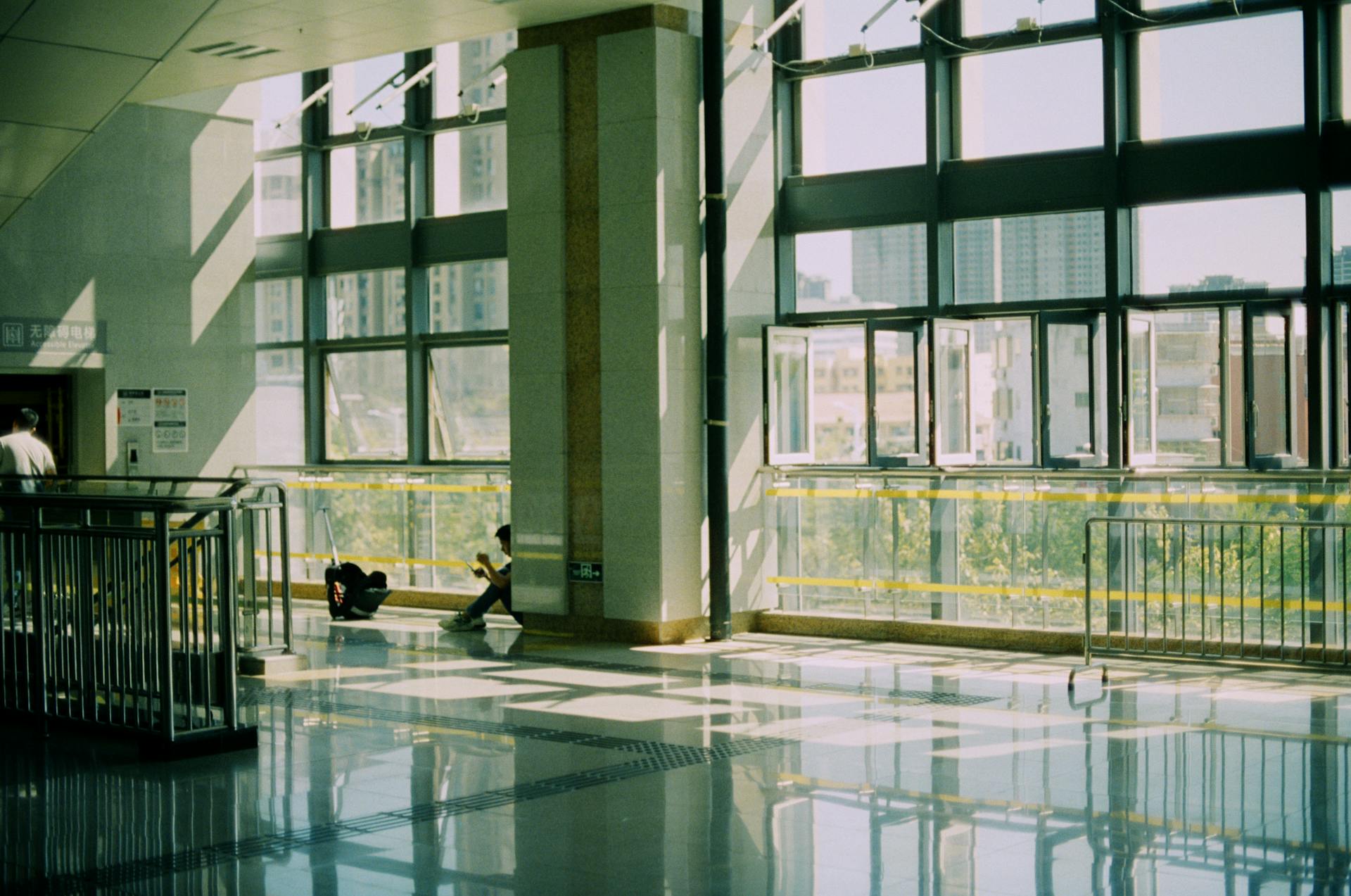 Bright indoor space with large windows and reflections on the floor, featuring modern architecture.