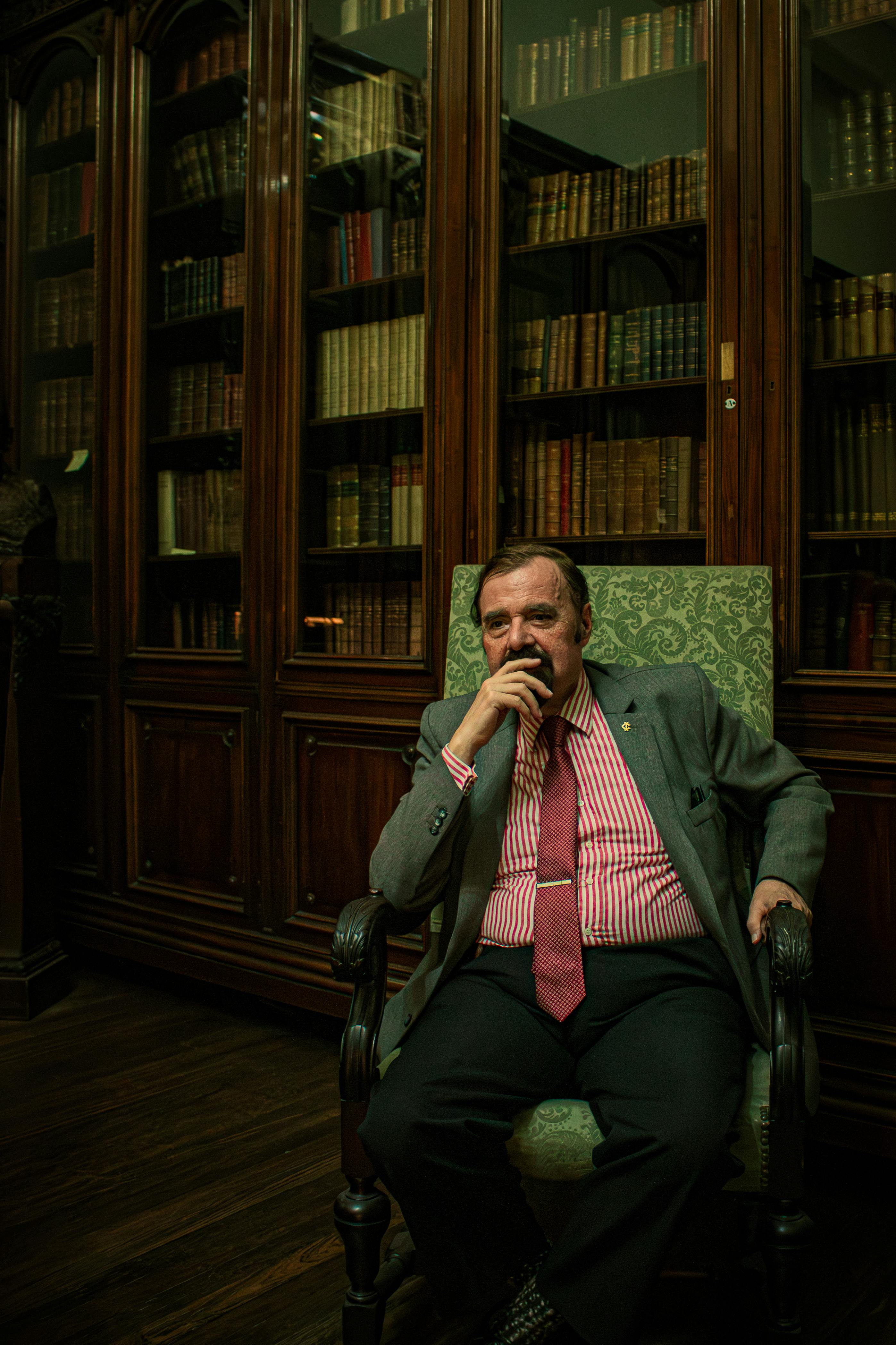 Elderly man in a sophisticated library setting, reflecting elegance and contemplation.