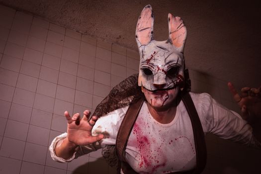 Close-up of a person in a bloody rabbit mask with ominous lighting.