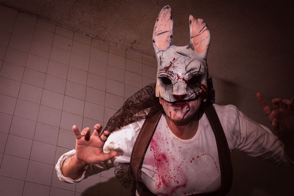 Close-up of a person in a bloody rabbit mask with ominous lighting.