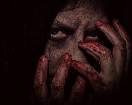 Close-up portrait of a person with dark makeup and bloody hands, exuding a chilling horror vibe.