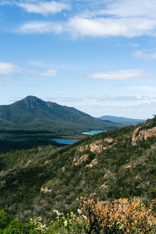 Free Beautiful view of a mountain range under a clear blue sky, with lush greenery and distant water body. Stock Photo