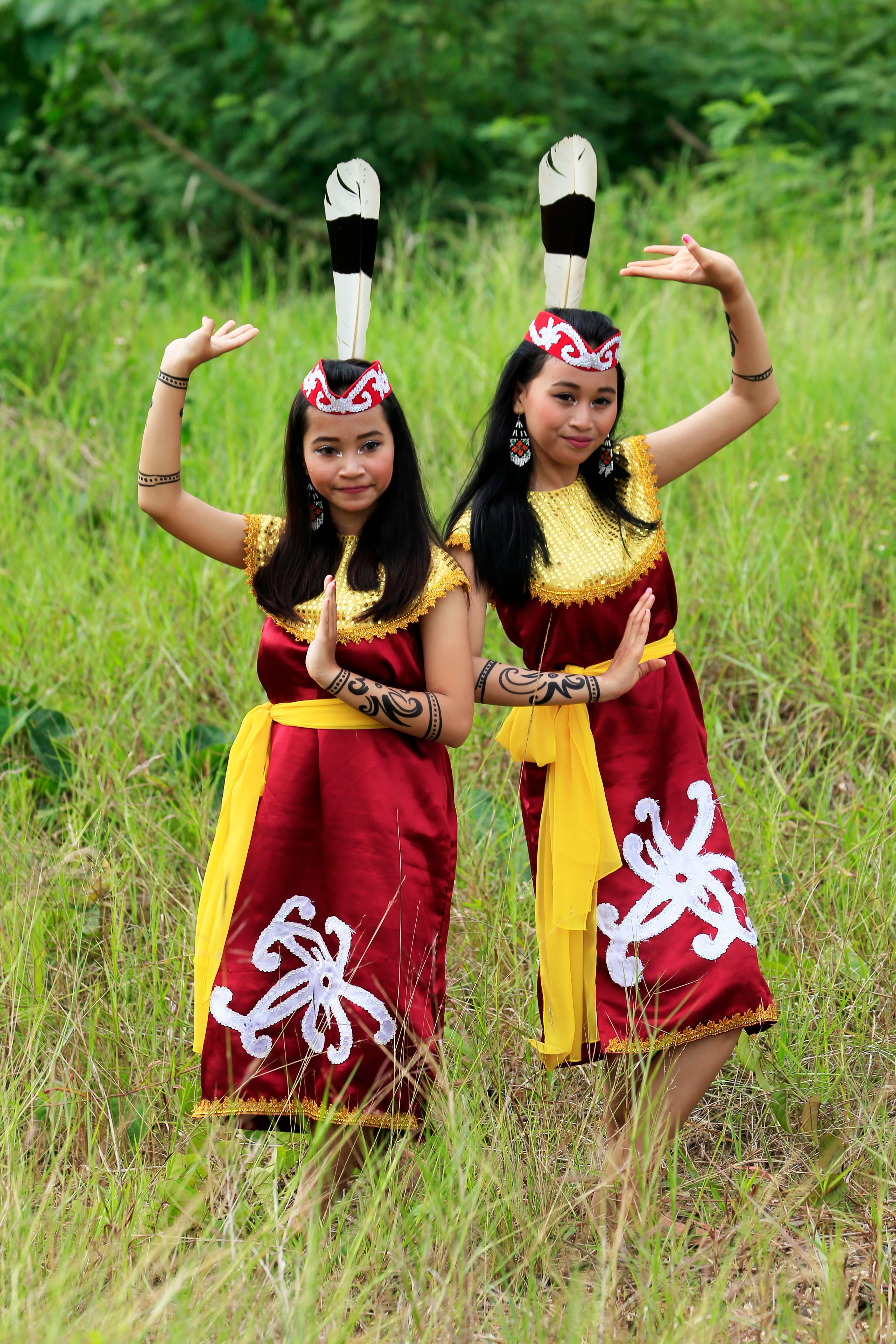 Two women performing a traditional dance in colorful cultural attire in an outdoor setting.