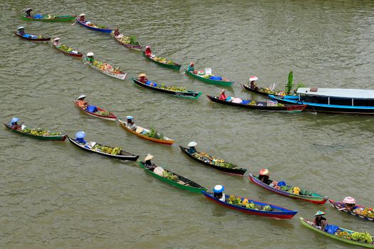 Aerial view of a vibrant floating market with multiple boats carrying goods and produce.