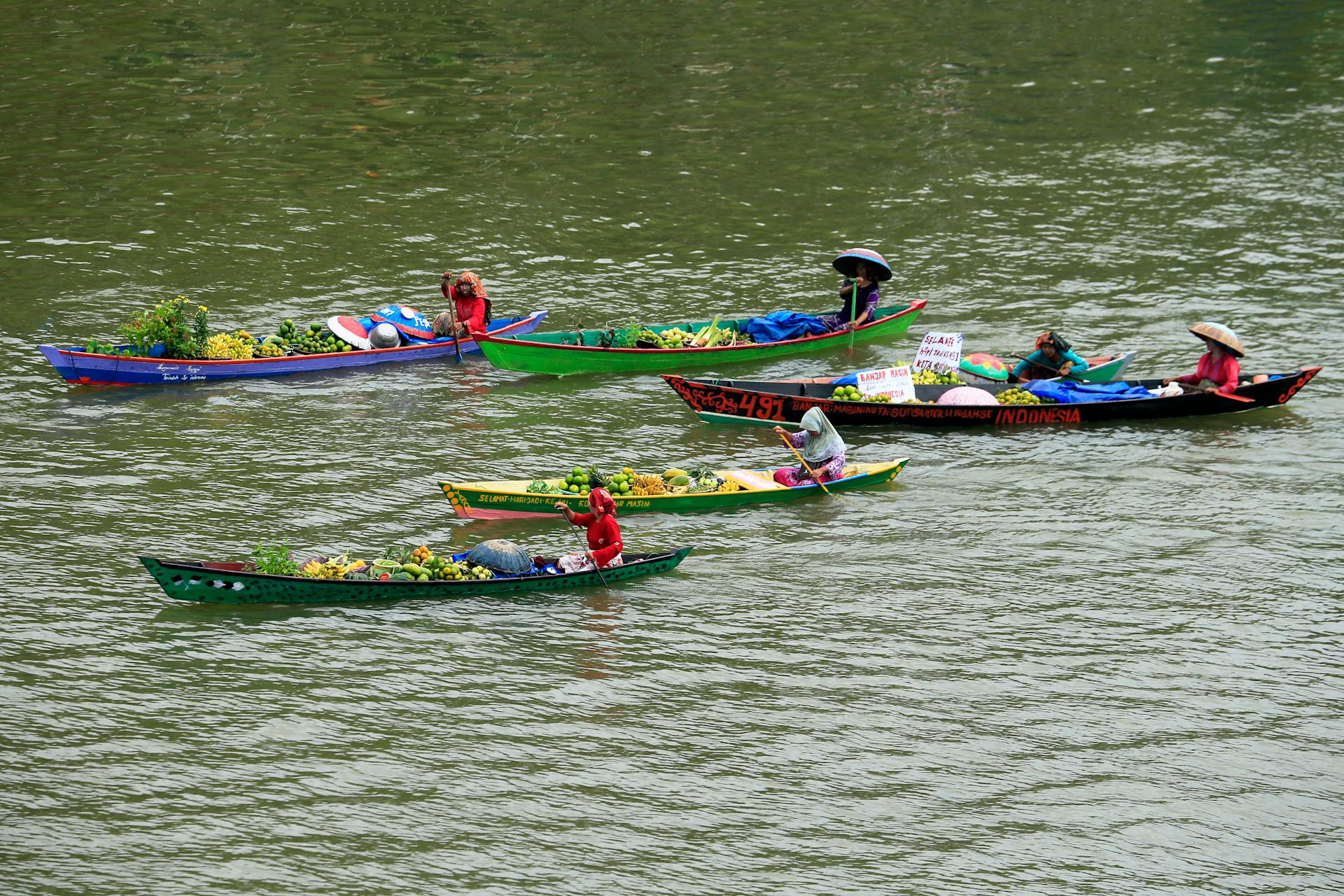 Vibrant scene of people trading goods on colorful boats at an Indonesian floating market.