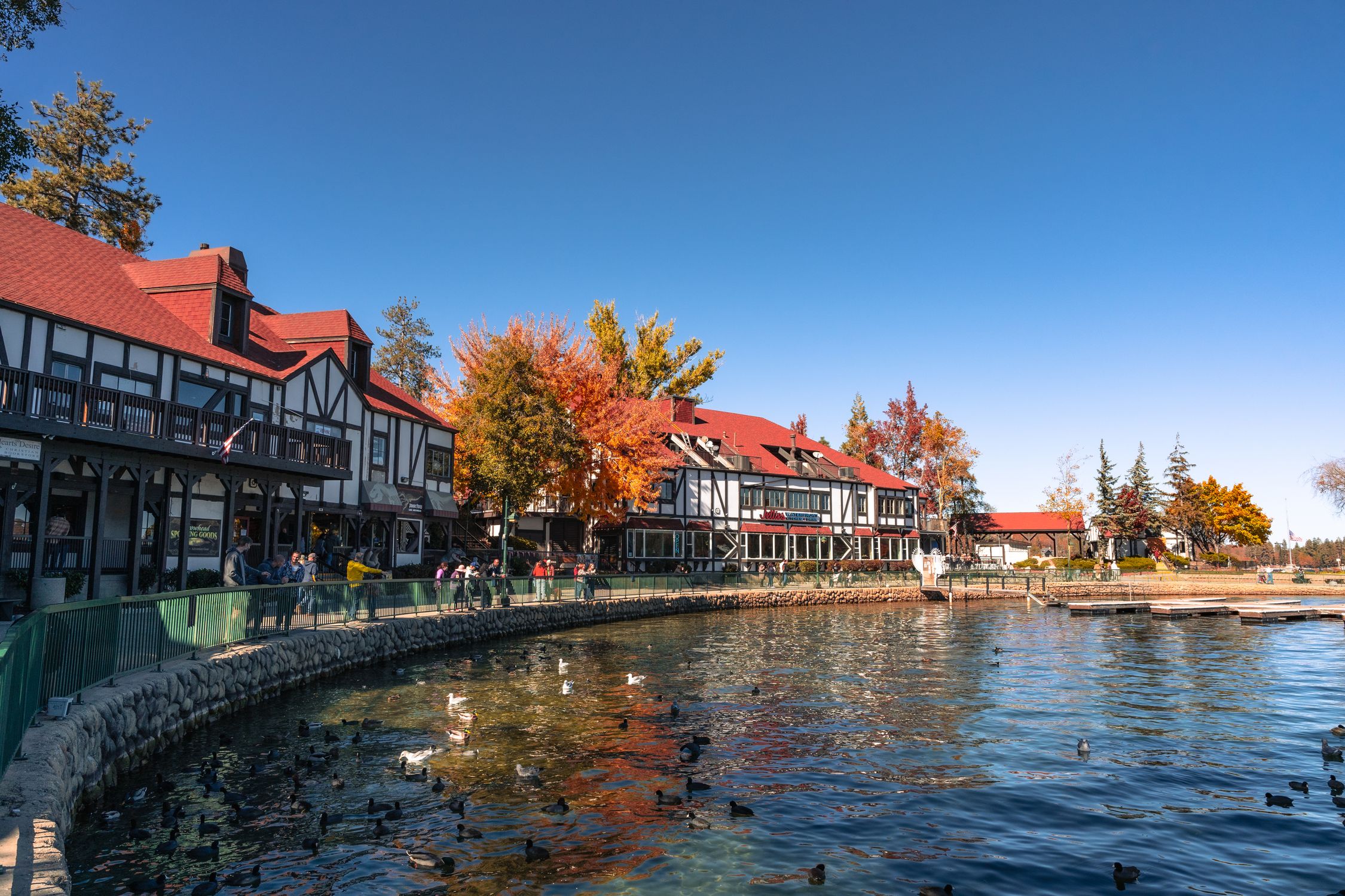 Picturesque Lake Arrowhead Village with autumn foliage and ducks by the lakeside.