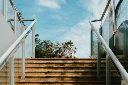 Free A serene stairway in the city leading towards blue skies and greenery, evoking urban escape. Stock Photo
