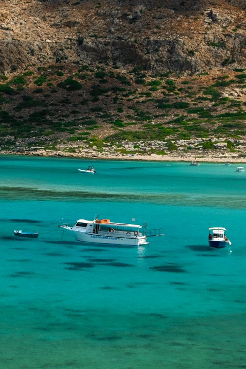 Free Explore serene azure waters and boats along Greece's breathtaking coastline. Stock Photo