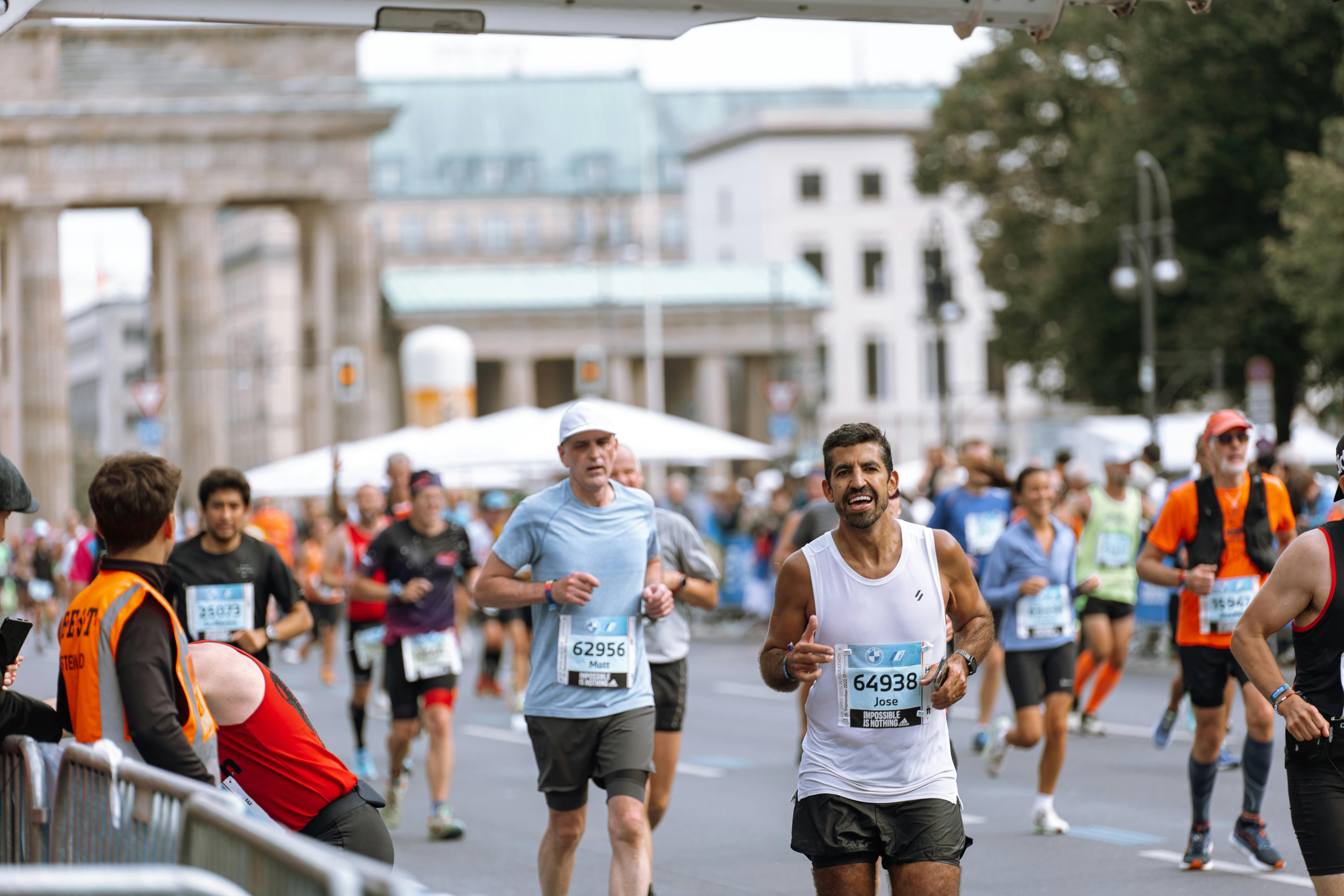 Runners cross finish line at Berlin Marathon, showcasing athletic determination.