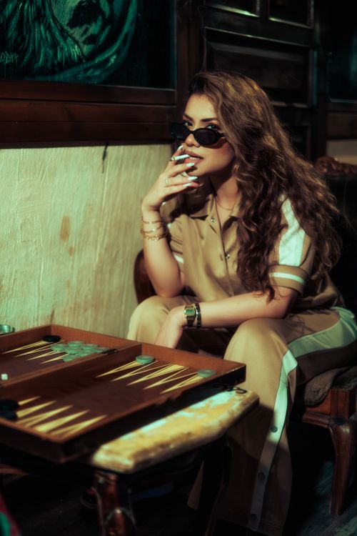 Free Woman contemplating backgammon move in cozy room, exuding elegance and style. Stock Photo