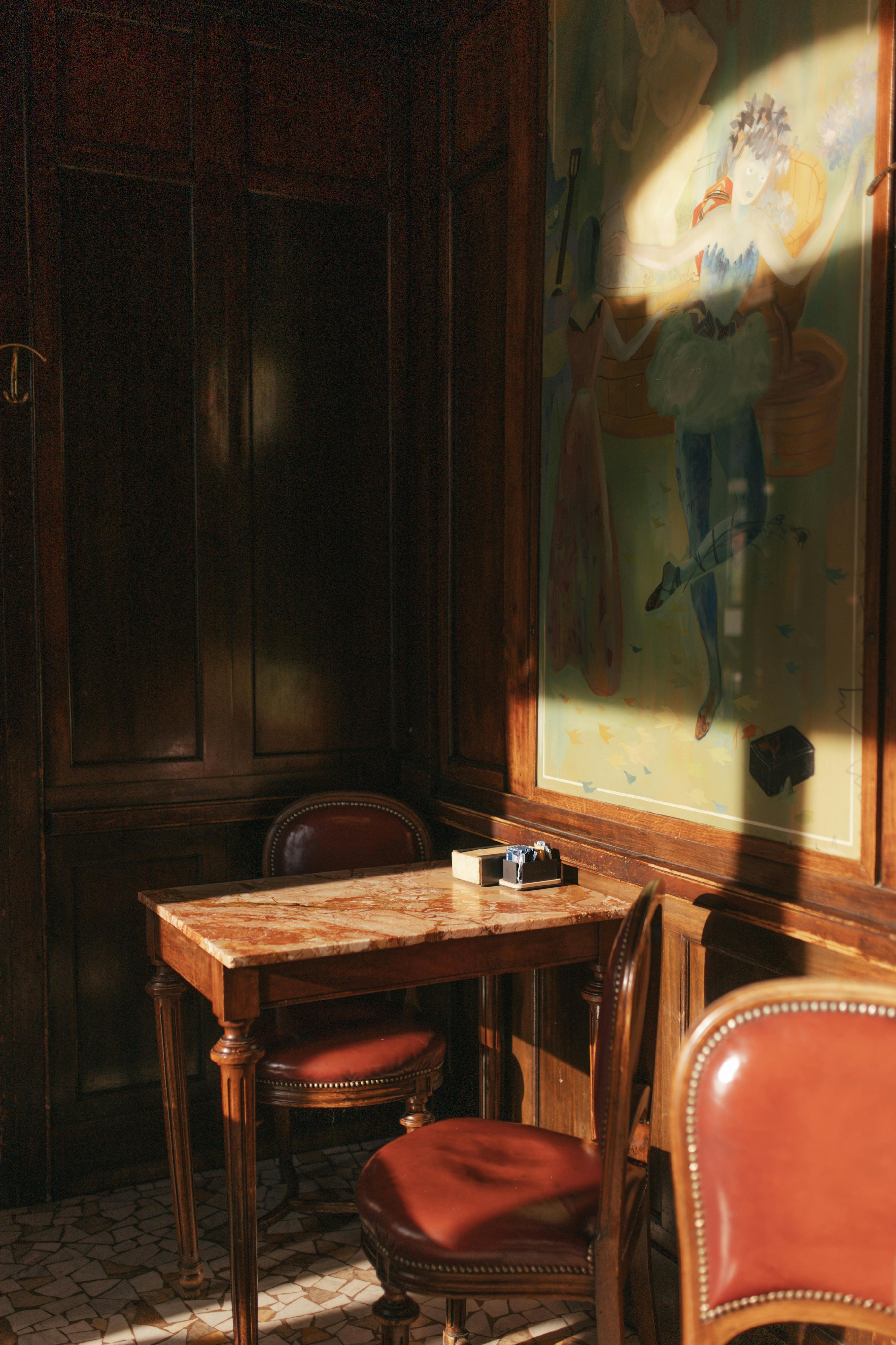 Elegant vintage café interior with classic furniture and art in soft sunlight.
