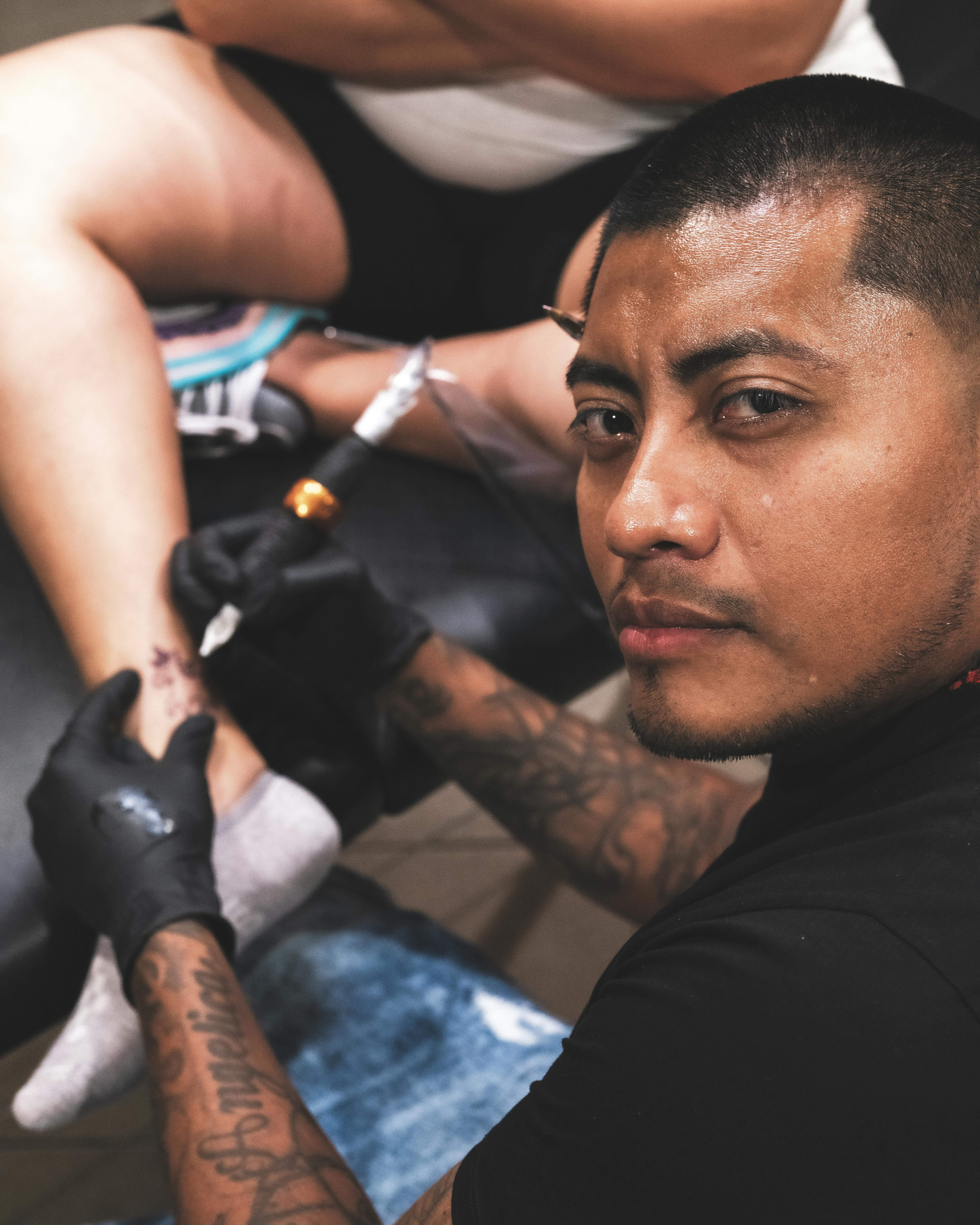 Man Giving a Person's Ankle a Tattoo