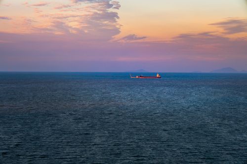 Free A distant cargo ship sails on the sea under a vibrant sunset in Fuzhou, Fujian Province, China. Stock Photo