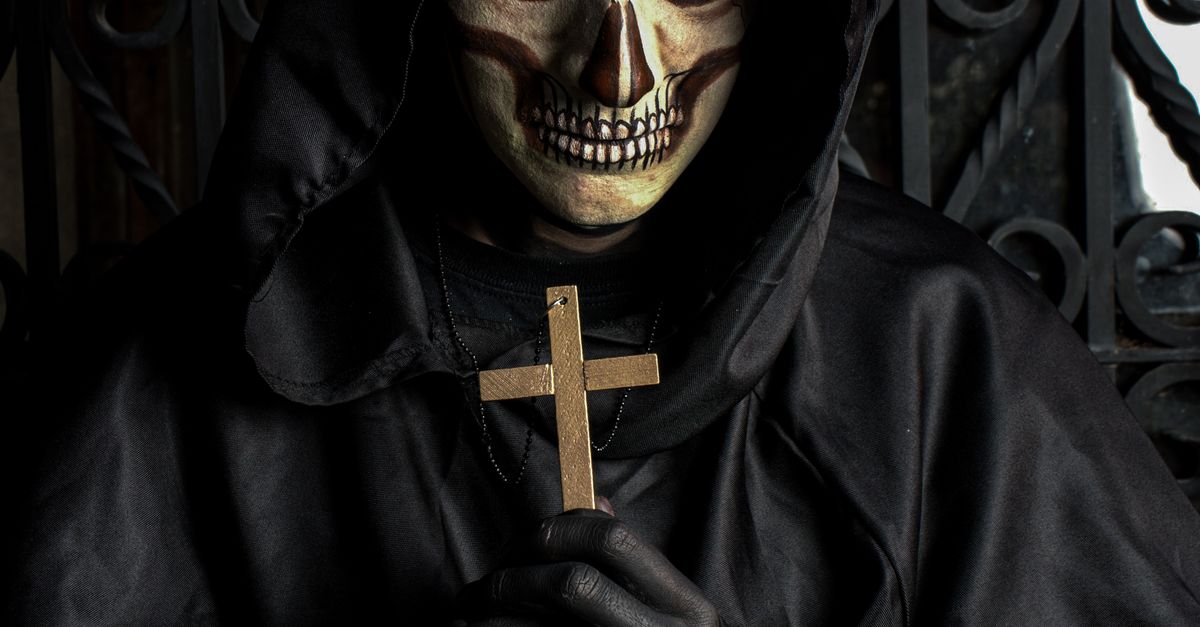 Creepy Hooded Figure with Cross in Dark Atmosphere · Free Stock Photo