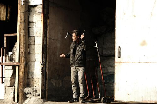 Free Man stands in a doorway holding a hand truck, looking to the side. Stock Photo