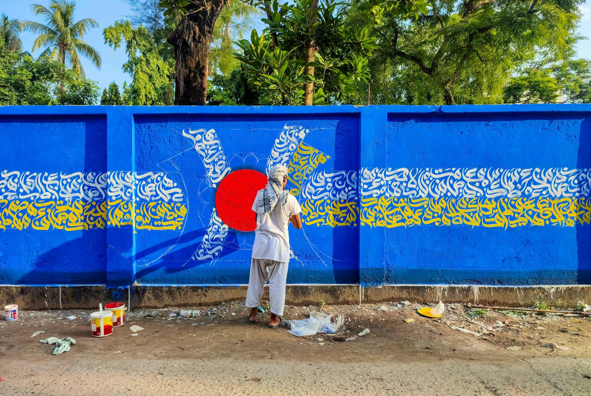 A street artist works on a vibrant mural featuring intricate designs and bold colors.