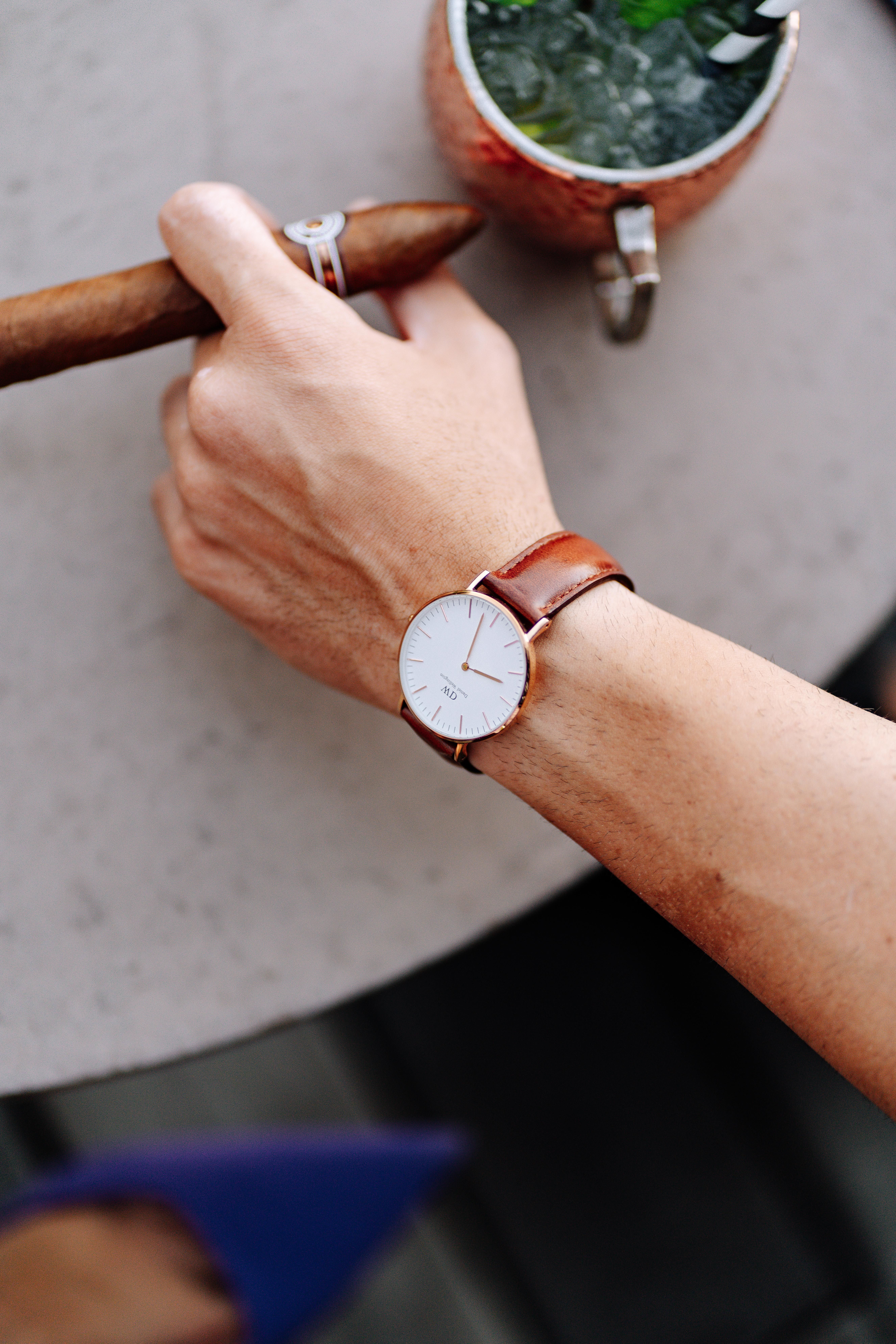 Close-up of a stylish analog wristwatch on a man's wrist holding a cigar in Tanzania.