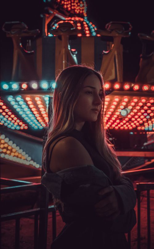Free Young woman in front of colorful carnival lights at night. Stock Photo