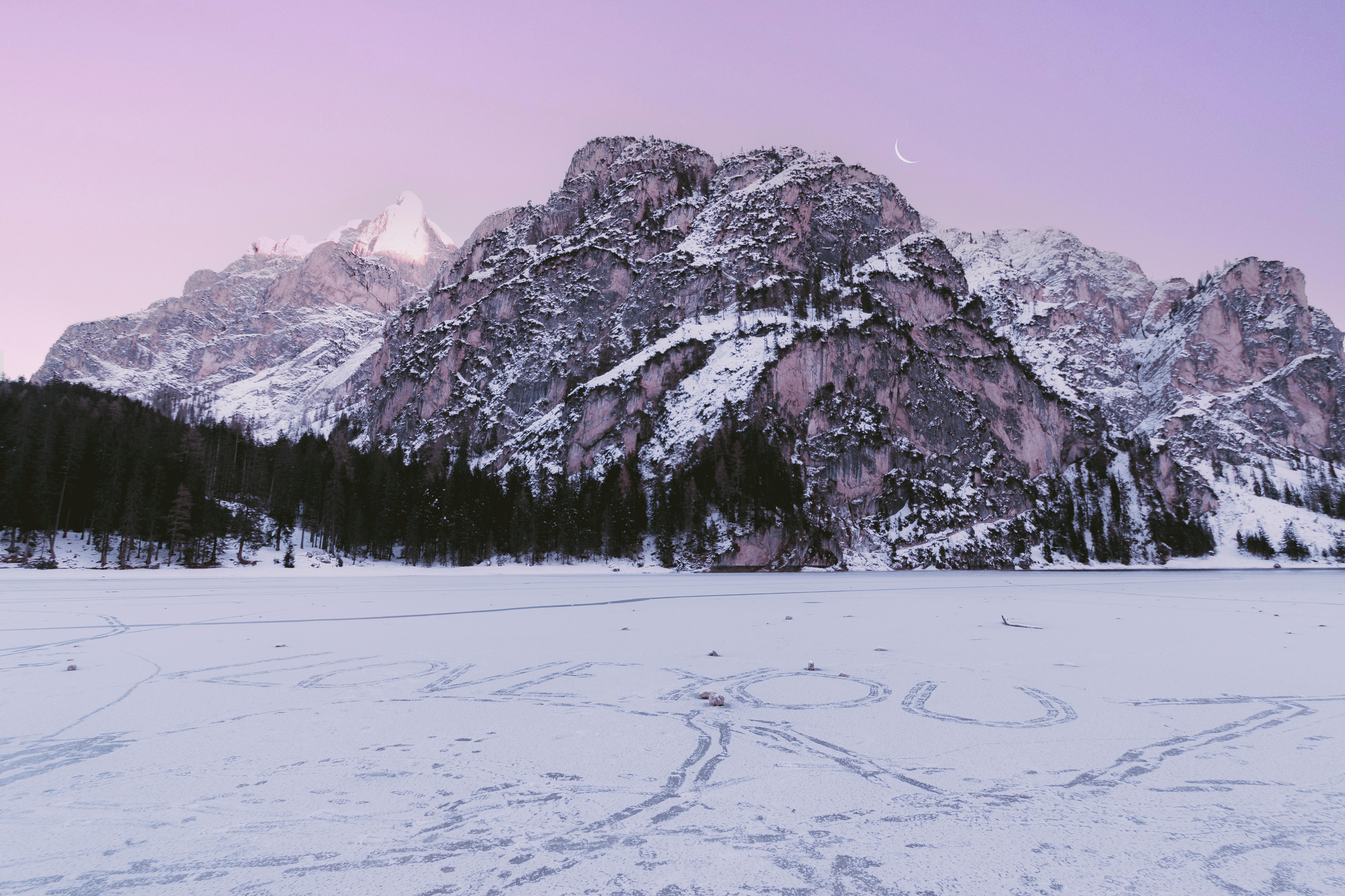 Snow-covered mountains under a twilight sky with text 'LOVE YOU' on frozen lake.