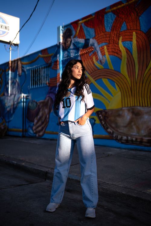 Free Young woman poses confidently by a colorful street mural in casual attire. Stock Photo