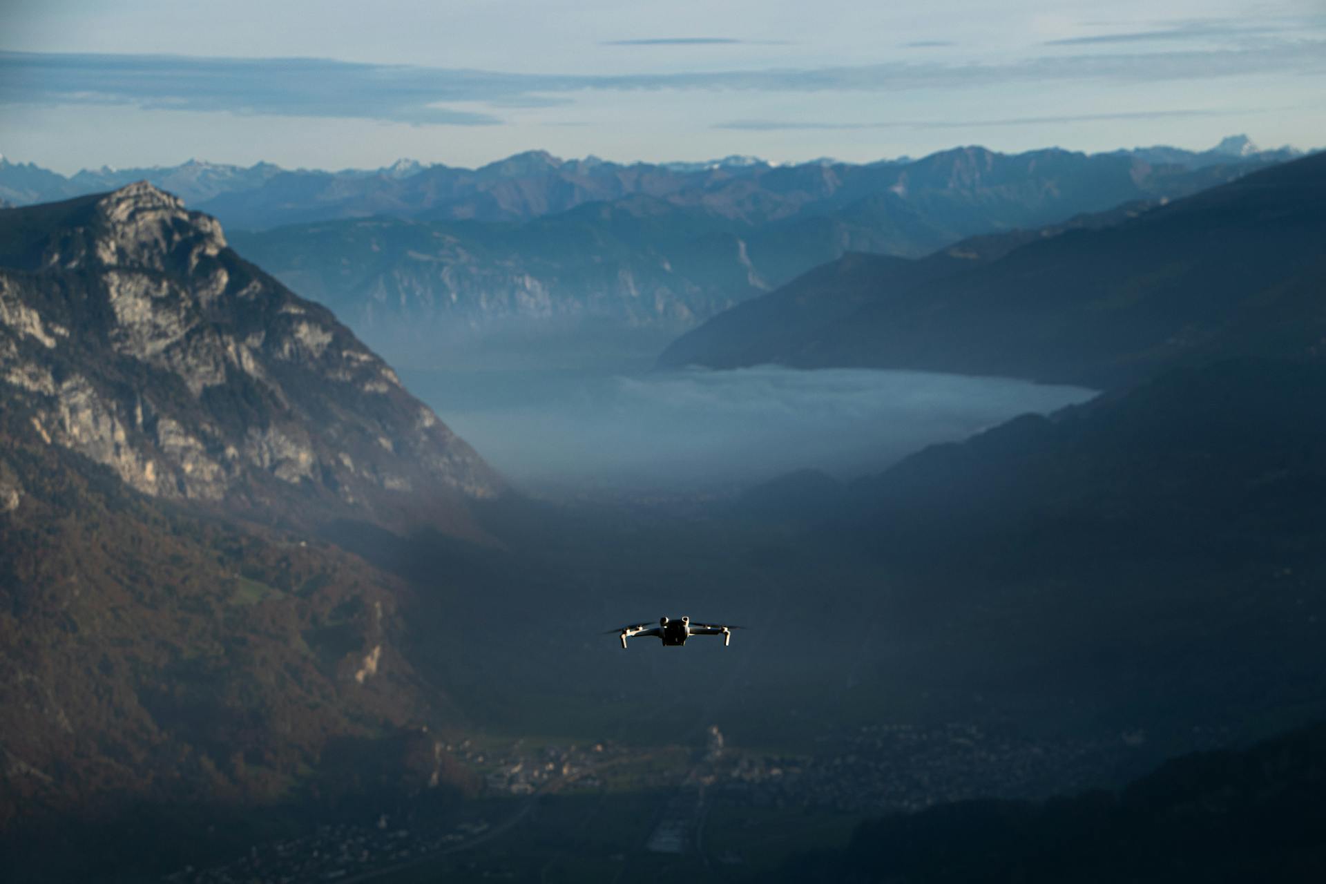 Drone flying through mountains over city