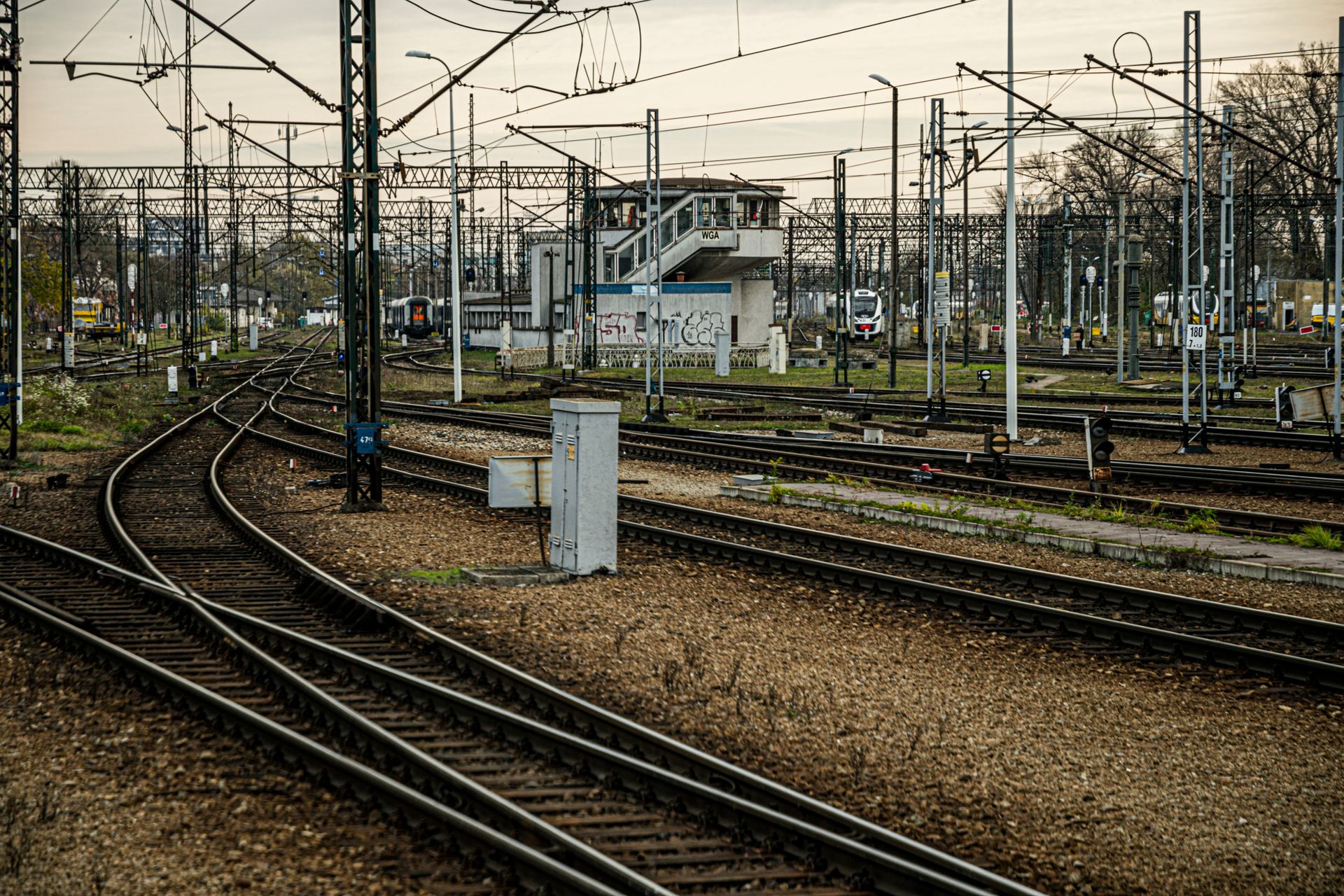 Complex railway junction with tracks and signal systems under a cloudy sky.