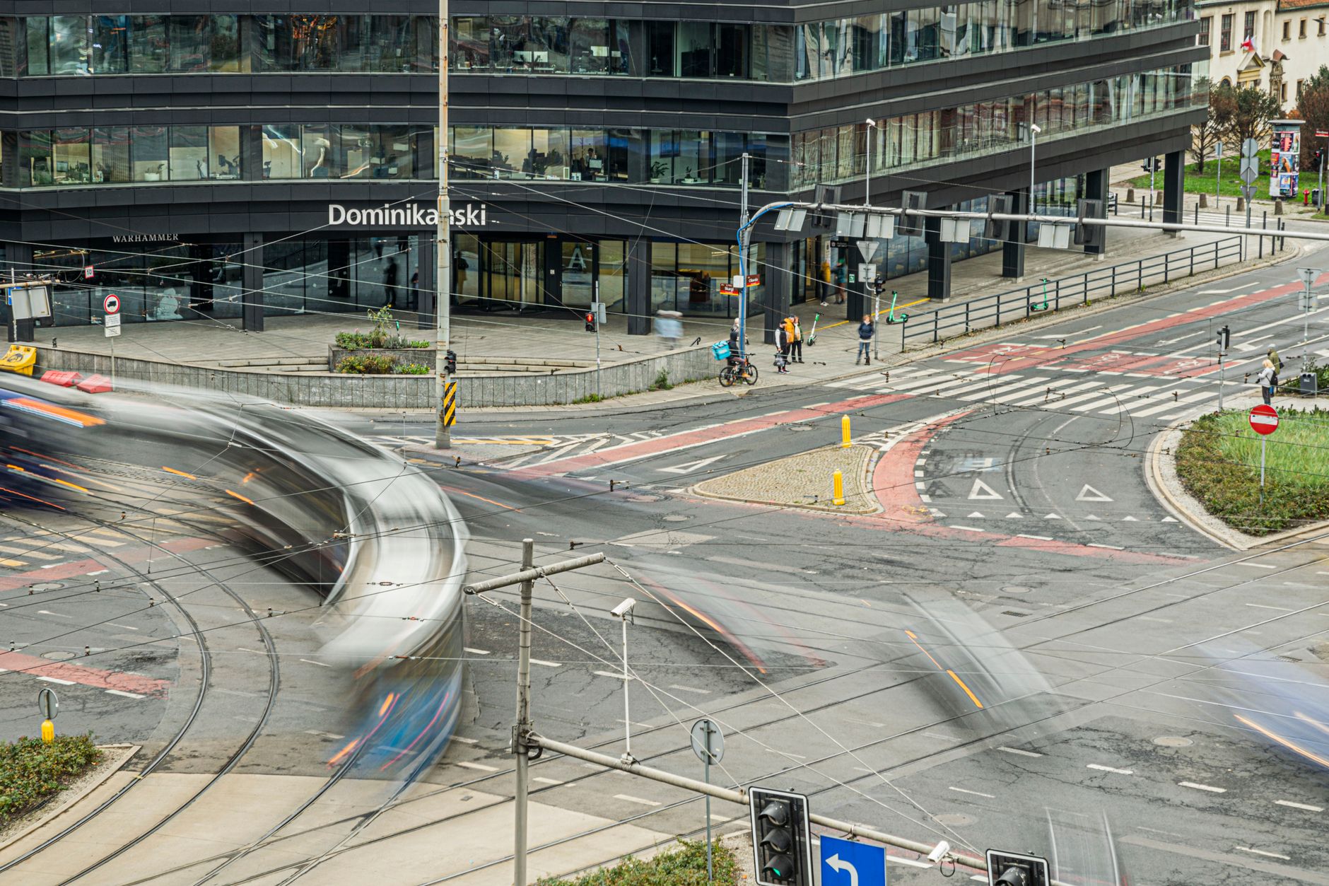 A busy intersection with motion blur captures urban life and movement, featuring modern buildings and traffic.
