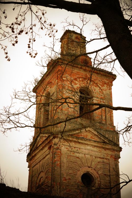 Free An old brick tower surrounded by bare branches on a moody day, conveying a vintage charm. Stock Photo