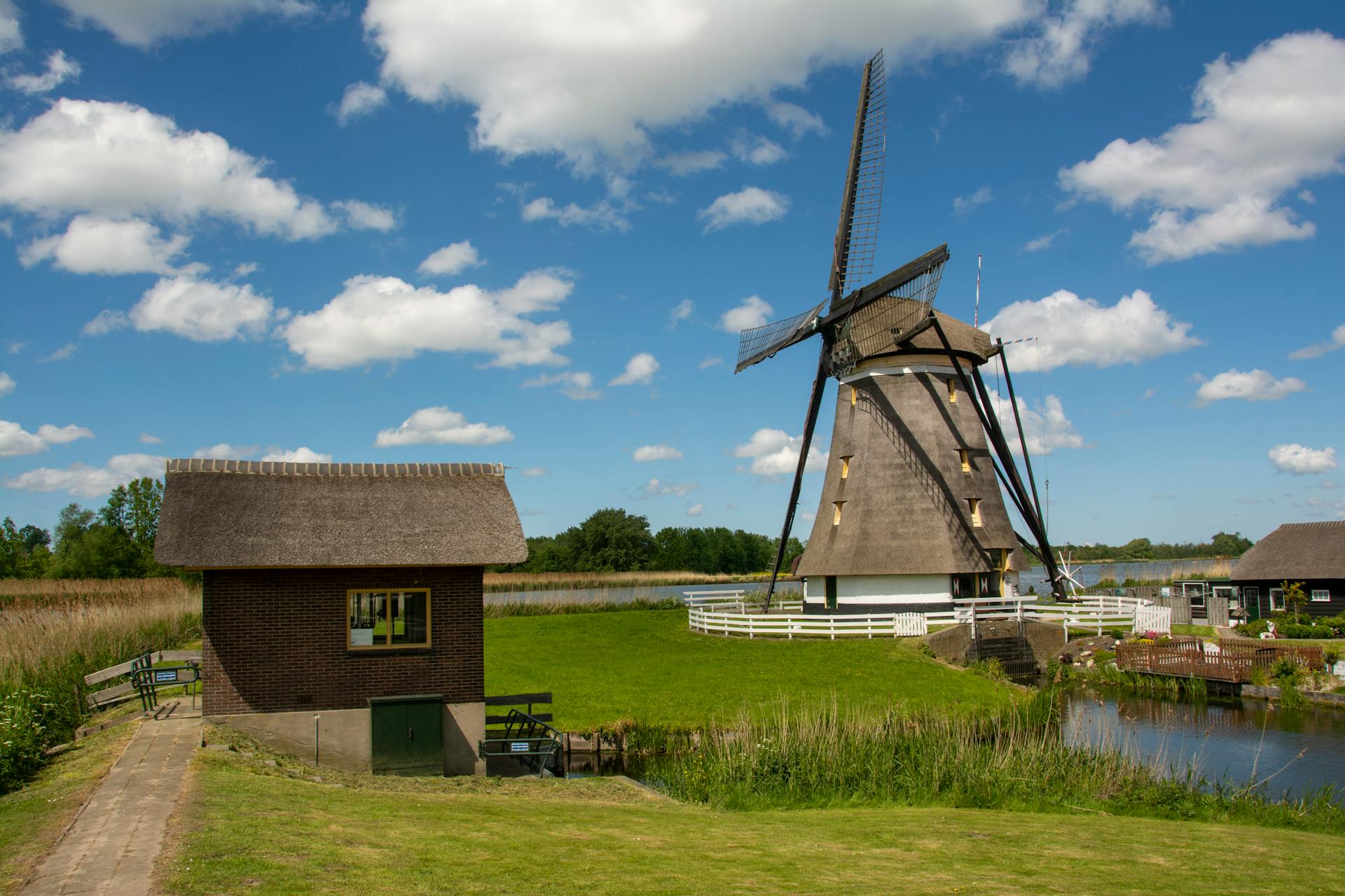 Scenic view of a traditional Dutch windmill surrounded by lush greenery and blue skies.