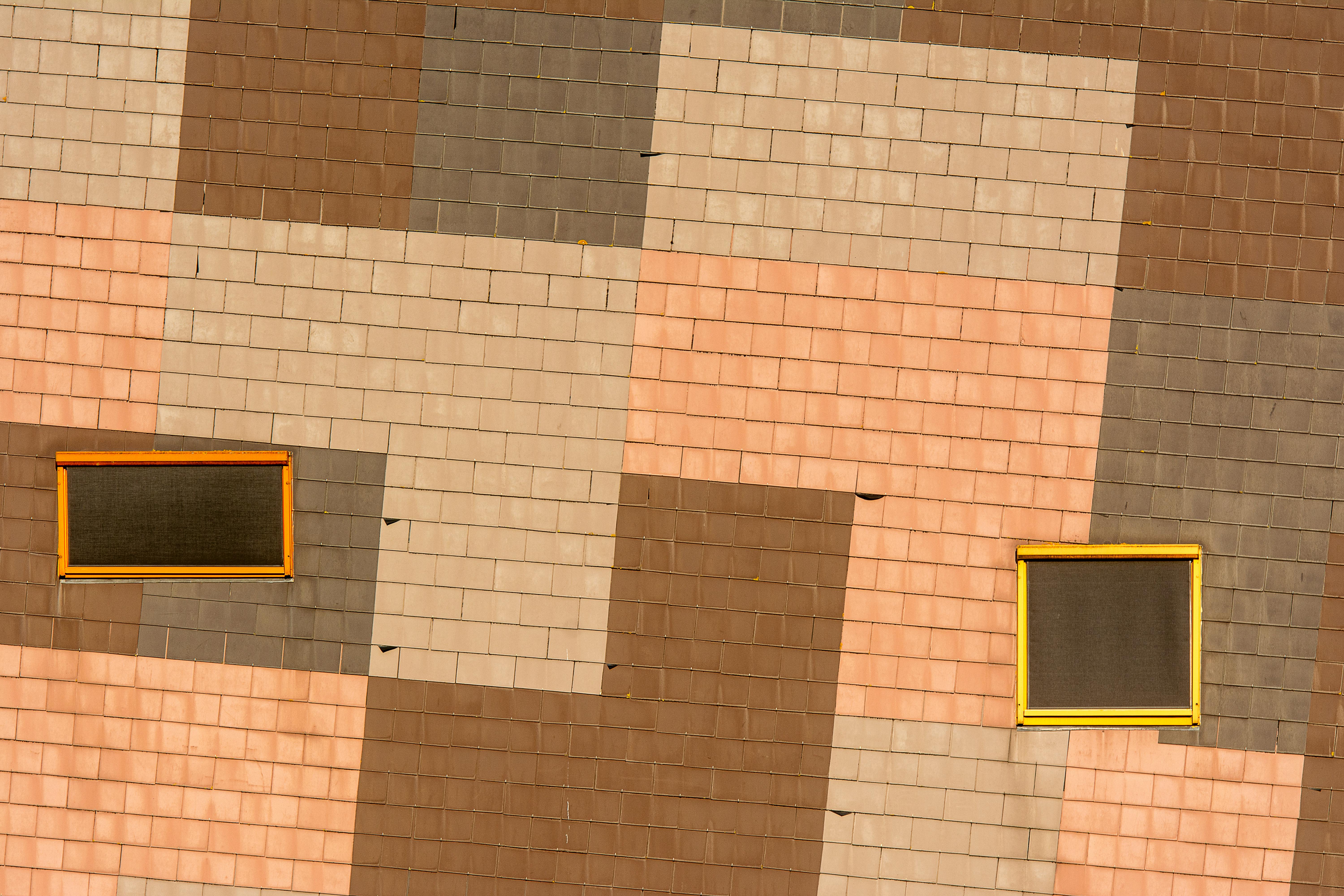 bezplatná Barevná cihlová zeď s geometrickým designem a dvěma žlutě orámovanými okny. Základová fotografie