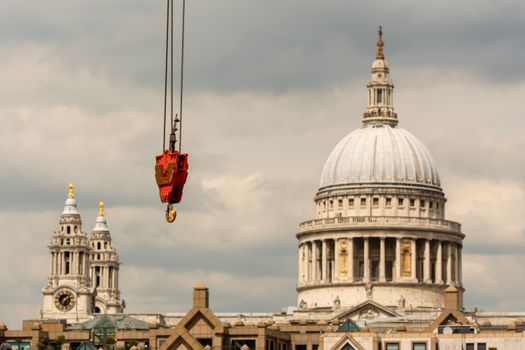 A crane hangs above St. Paul's Cathedral in London, with cloudy skies in the background.