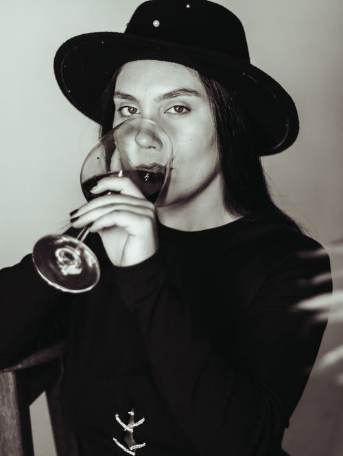 Free Elegantly dressed woman in a black hat sipping wine, showcasing a chic and modern aesthetic. Stock Photo