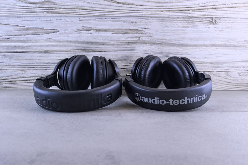 Pair of Audio-Technica headphones displayed on a textured wooden background.