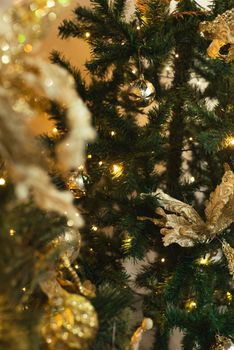 Close-up of a beautifully decorated Christmas tree with gold ornaments and warm lights.