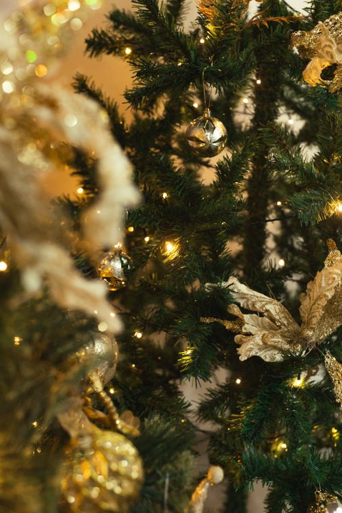 Free Close-up of a beautifully decorated Christmas tree with gold ornaments and warm lights. Stock Photo
