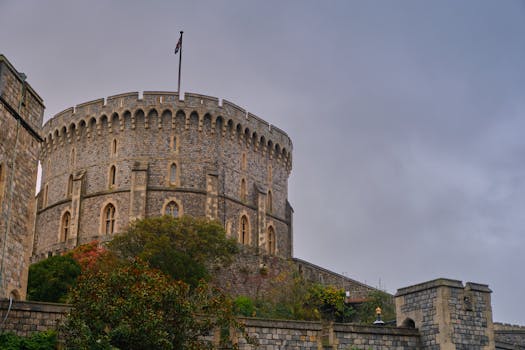 A moody view of Windsor Castle's stone tower with an overcast sky backdrop. by Nick