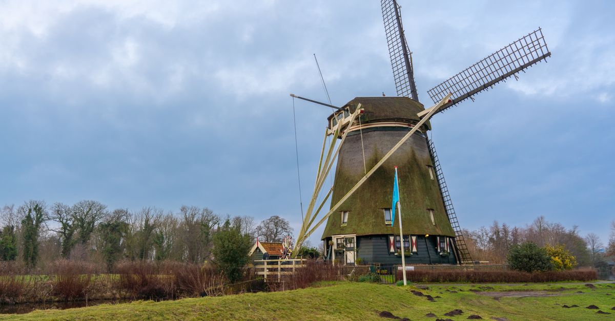 Classic Dutch windmill set against a scenic Amsterdam countryside view.
