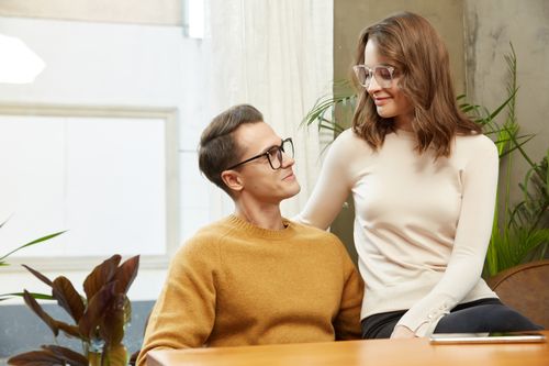 Free A fashionable couple wearing glasses, sitting together indoors with a warm atmosphere. Stock Photo