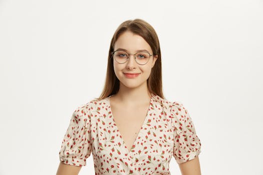 A stylish portrait of a smiling woman wearing glasses and a floral dress.