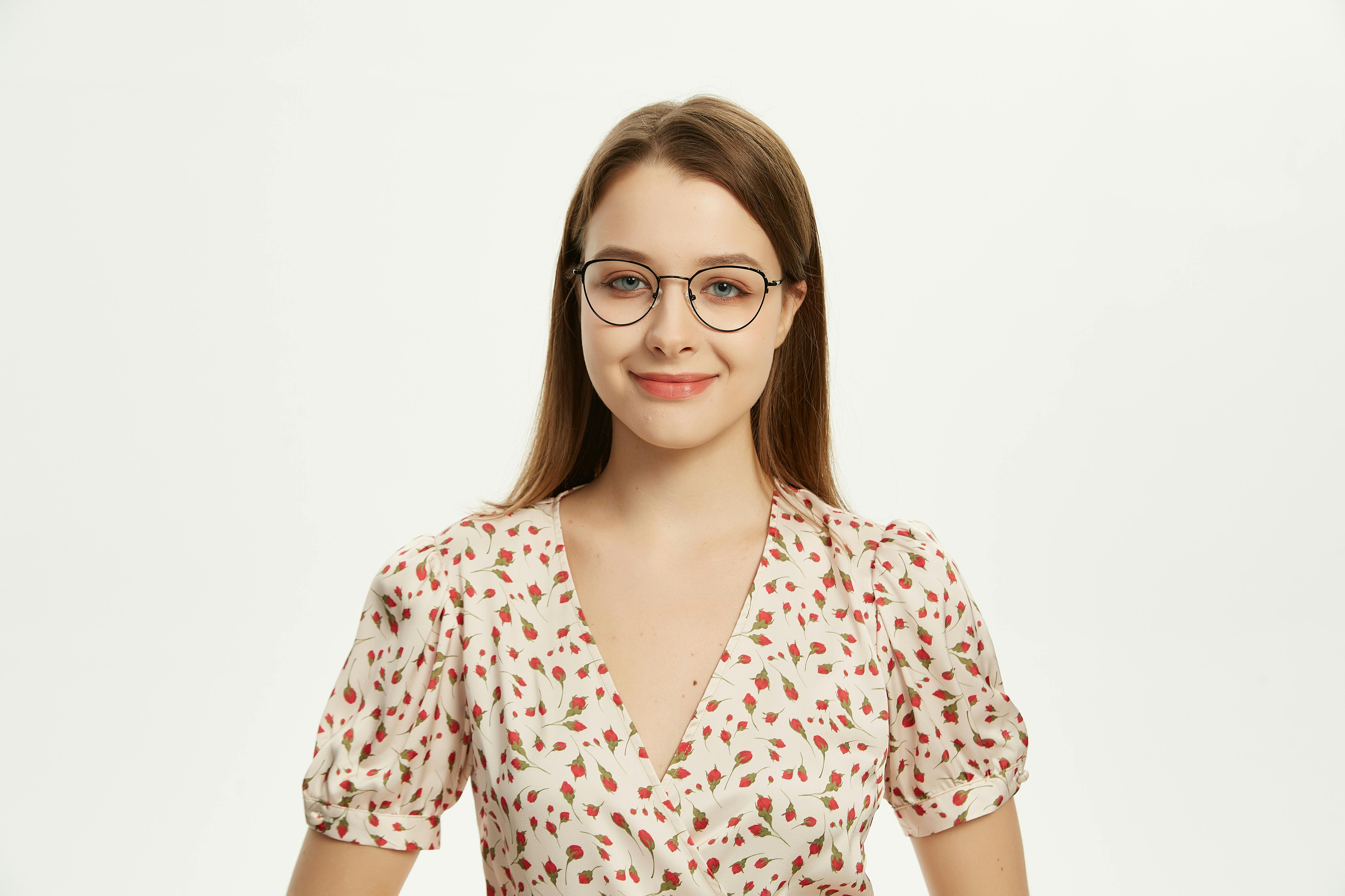 Kostenlos Ein stilvolles Porträt einer lächelnden Frau mit Brille und geblümtem Kleid. Stock-Foto