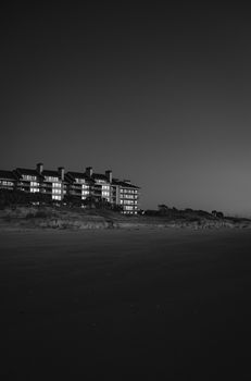 Monochrome image of coastal apartment buildings under night sky, serene mood.