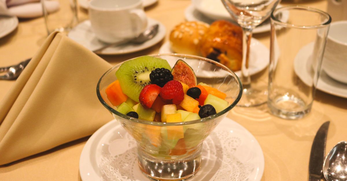 Uma salada de frutas colorida sobre uma mesa posta para jantar em um restaurante.