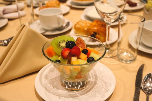 A colorful fruit salad on a table set for dining in a restaurant.