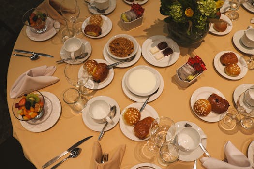 Top view of a breakfast table with pastries, fruit salad, and beverages, showcasing an elegant dining setting.