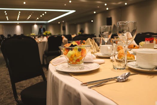 Elegant banquet table setting with fruit salad and glassware, ideal for events or weddings.