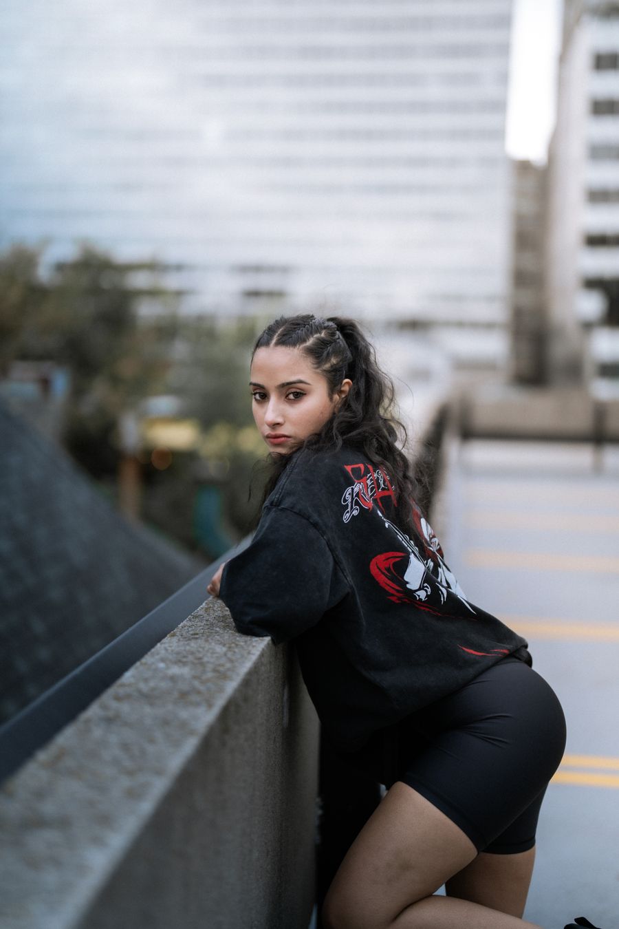 Urban portrait of a woman wearing black streetwear near a city backdrop